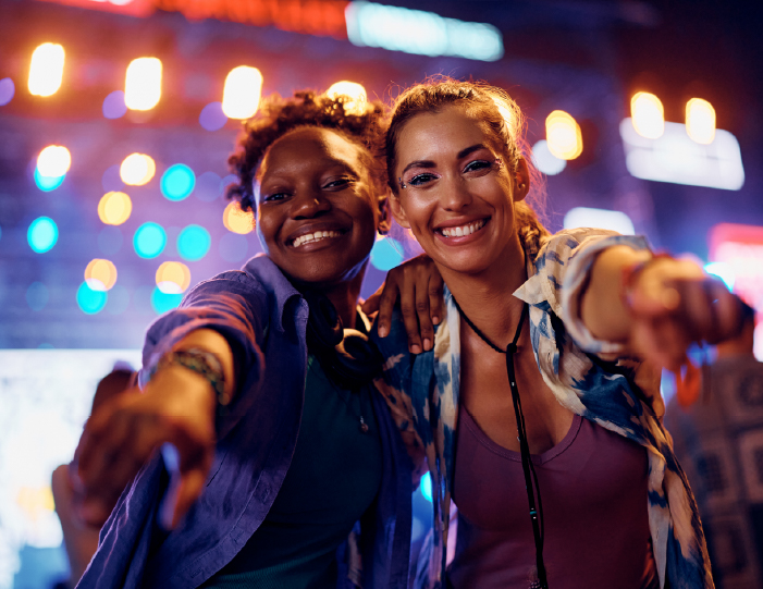 Two friends smiling together at a night out near Meadows Apartments - Universal City, TX
